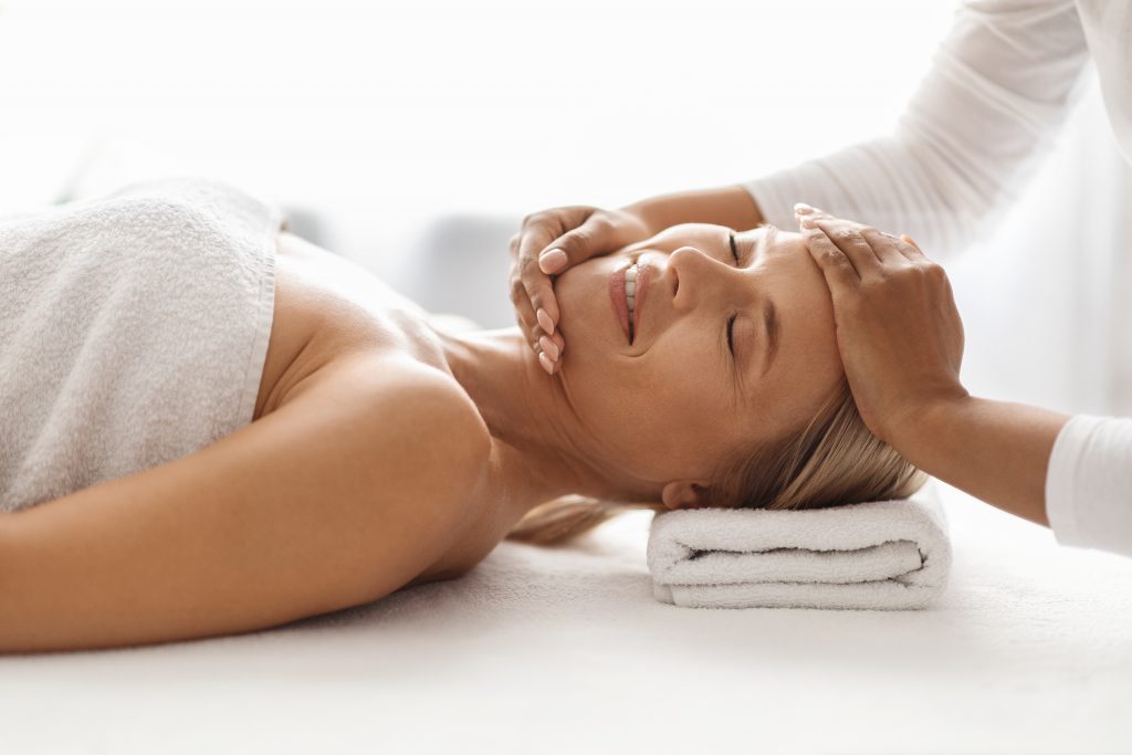 Professional face-lifting massage for mature skin: Experienced beautician treats attractive woman with premium techniques in the spa, close-up of the anti-aging treatment