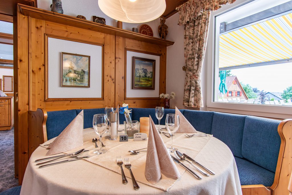 Classic restaurant area with elegantly set table and cozy round bench in the Wellnesshotel Hohenrodt