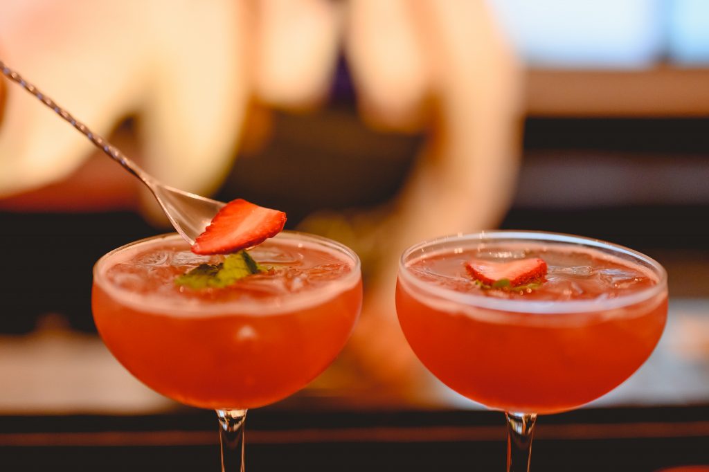 A bartender prepares a cocktail and decorates it in a martini glass for an appealing presentation at the bar of a wellness hotel