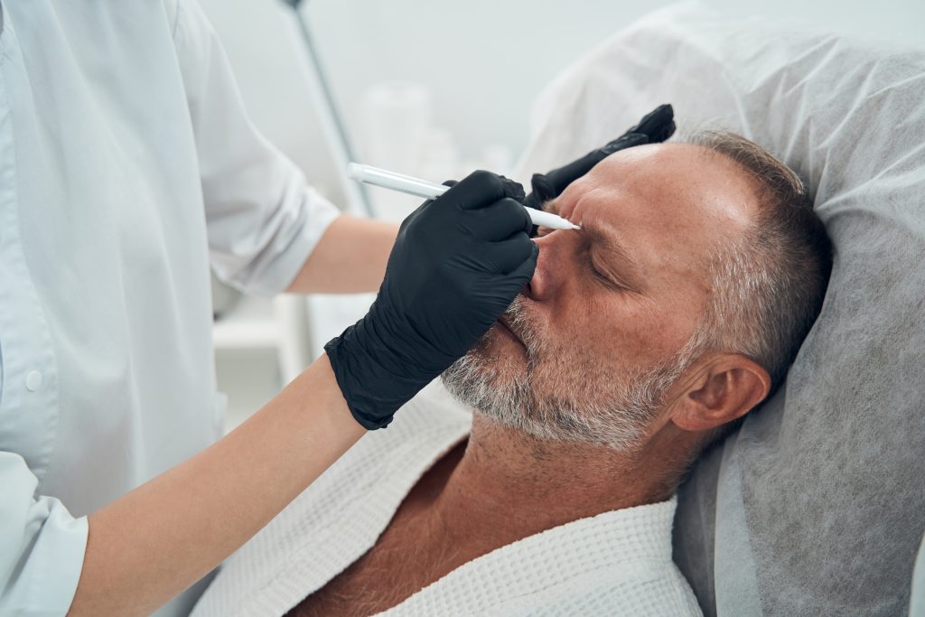 A male client receiving a skin cleansing treatment in the spa area.