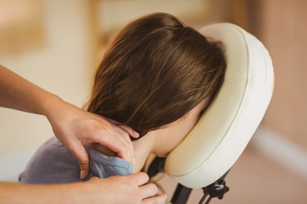 Junge Frau genießt eine wohltuende Antistress-Massage im Sessel im modernen Therapieraum