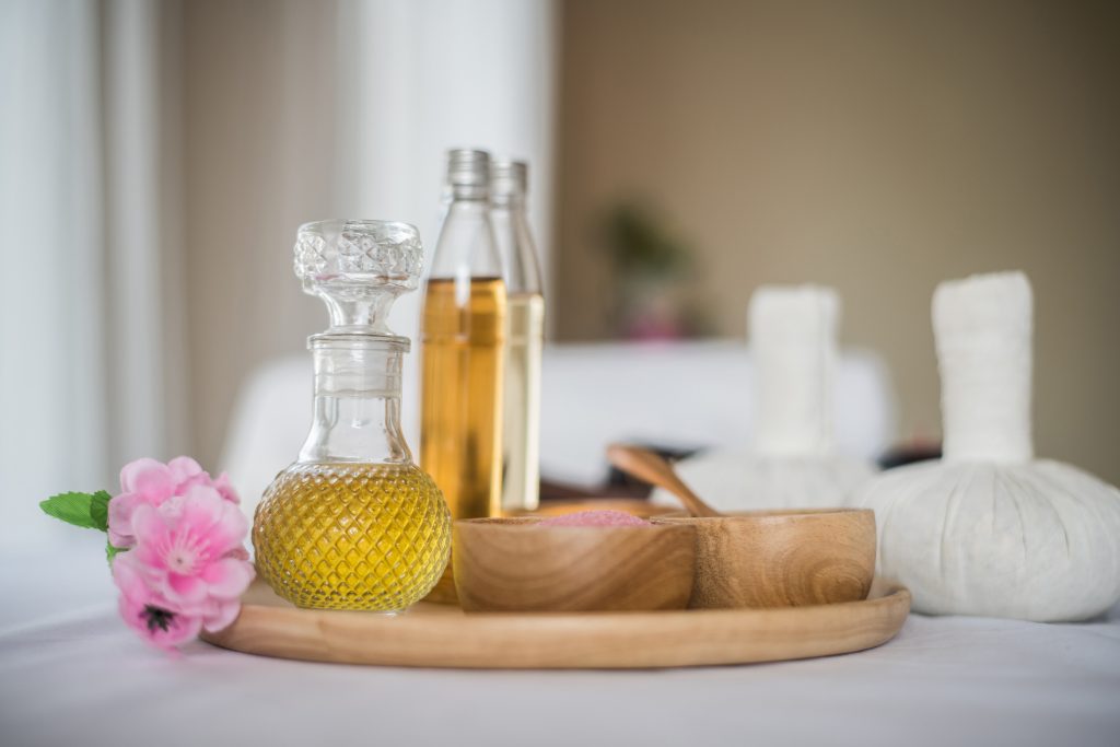 Aroma-Öle in Flaschen mit Massagestempeln und Holzschüsseln mit Salzen für Aromatherapie und Entspannung
