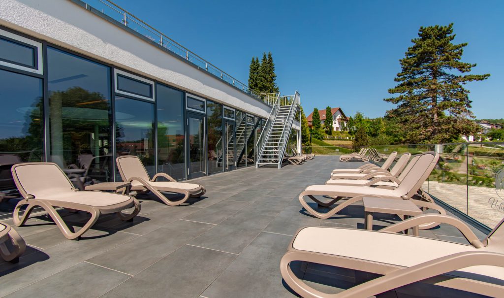 Balcon de détente avec chaises longues confortables et vue panoramique à l'hôtel de bien-être Hohenrodt