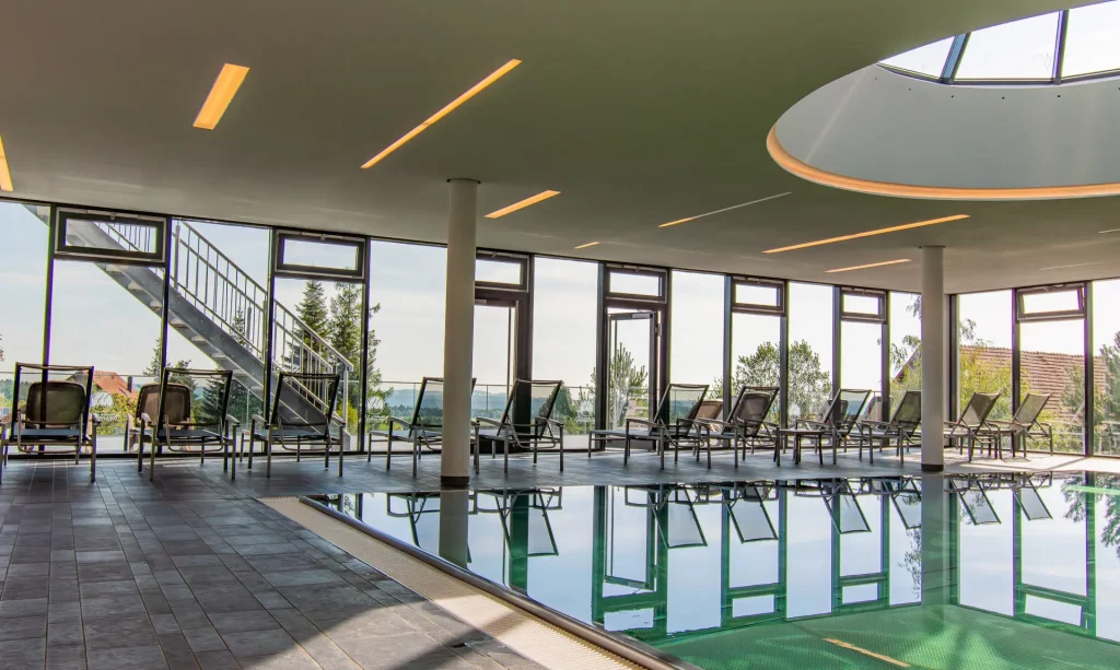 Relaxed atmosphere in the pool area with comfortable loungers in front of a spacious window front and natural light
