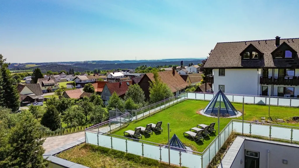 Aerial view of the Wellnesshotel Hohenrodt with hotel building, well-kept lawn and panoramic view of the surrounding nature.
