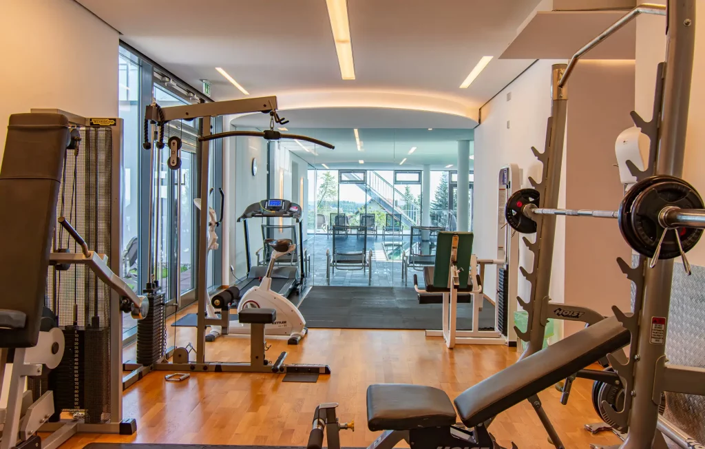 Wellness fitness room in the Wellnesshotel Hohenrodt with modern training equipment and a view of the pool area