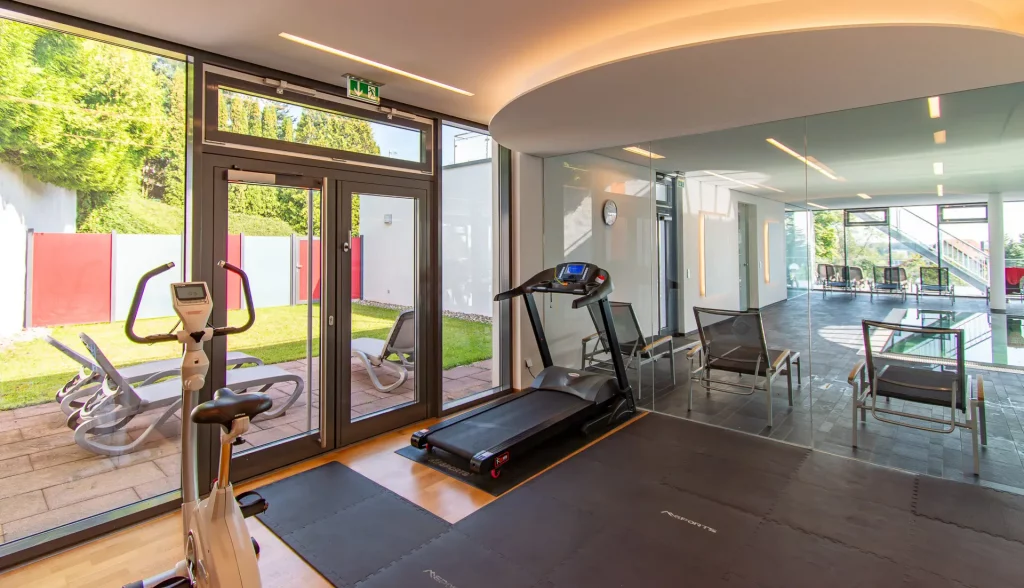 Wellness fitness room at Wellnesshotel Hohenrodt with a view of the pool area and large window facade