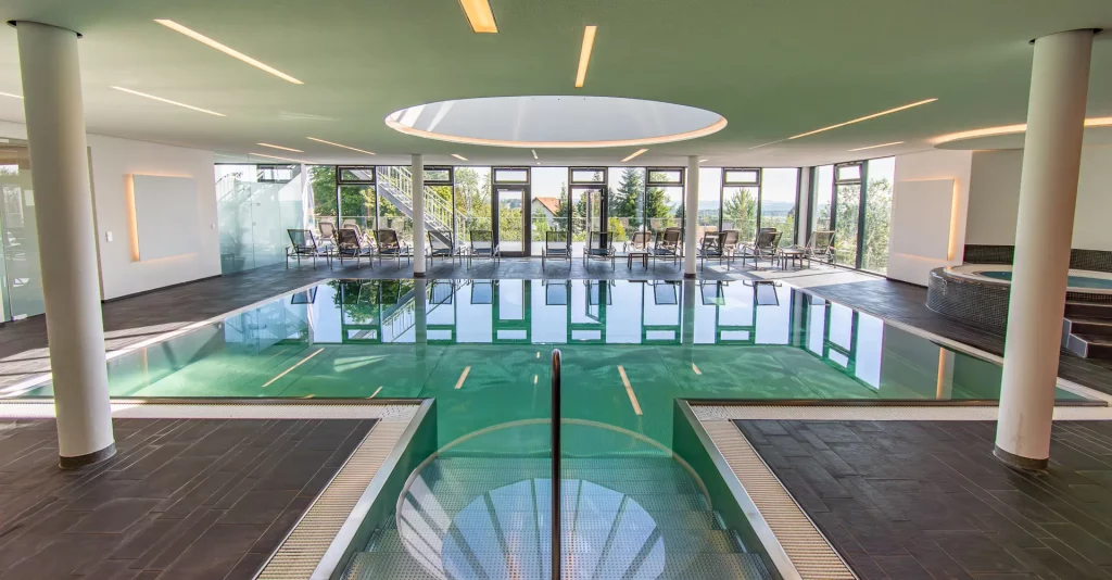 Wellnesspoolbereich im Wellnesshotel Hohenrodt komplettansicht bei Tageslicht mit Liegen und großer Fensterfront