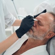 A male client receiving a skin cleansing treatment in the spa area.