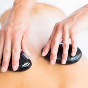 Masseur führt eine Hot-Stone-Massage am Rücken einer Frau im Spa durch