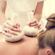 Kräuterstempel-Massage mit einem Tuch, das mit Heilkräutern gefüllt ist, für eine entspannende und therapeutische Behandlung