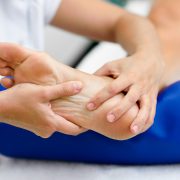 Weibliche Masseurin untersucht ihre Patientin für eine medizinische Fußmassage